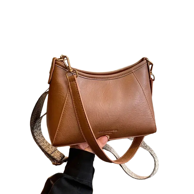 Brown leather crossbody shoulder bag for women with tan leather body and a curved top with patterned strap