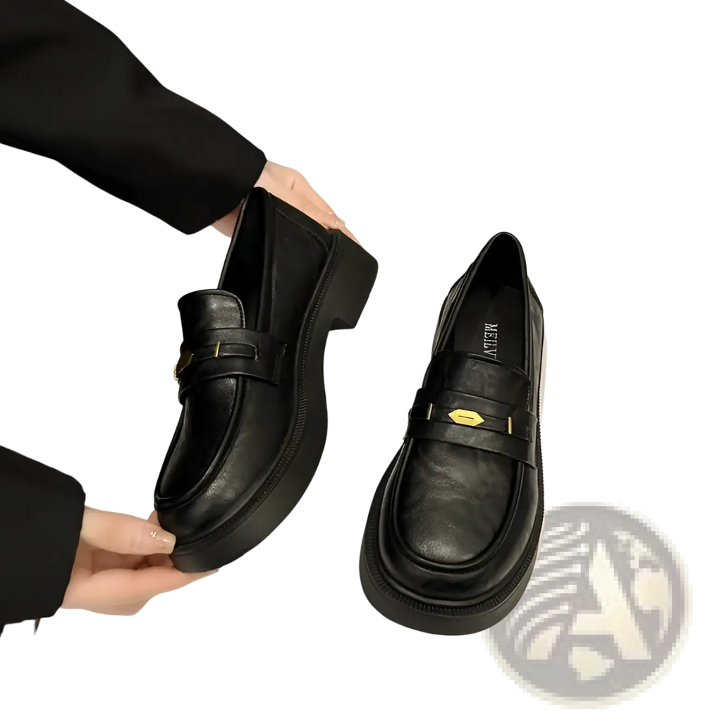 Black leather loafers with chunky sole and gold-tone buckle detail creating a bold and stylish look