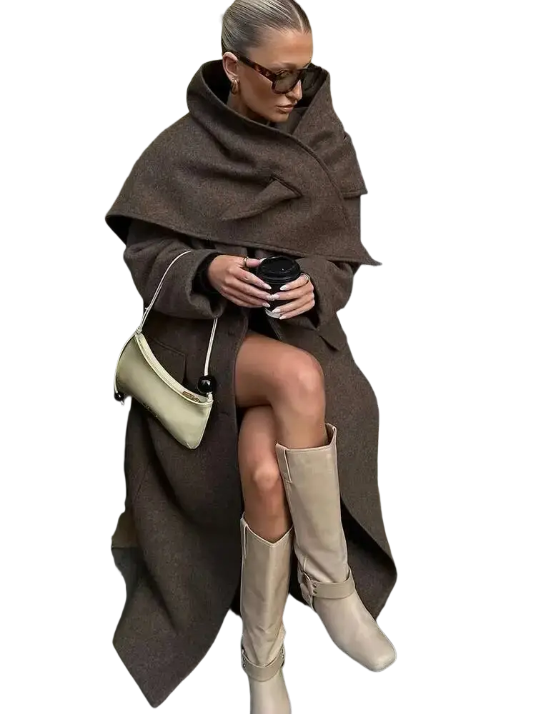 Cream-colored leather crossbody bag with minimalist design and black spherical hardware paired with brown wool blend overcoat for winter commuters