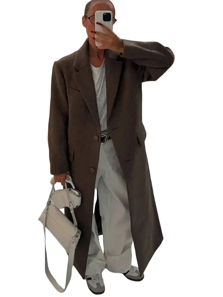 A sleek off-white leather handbag with structured design and silver hardware complementing a brown wool blend overcoat