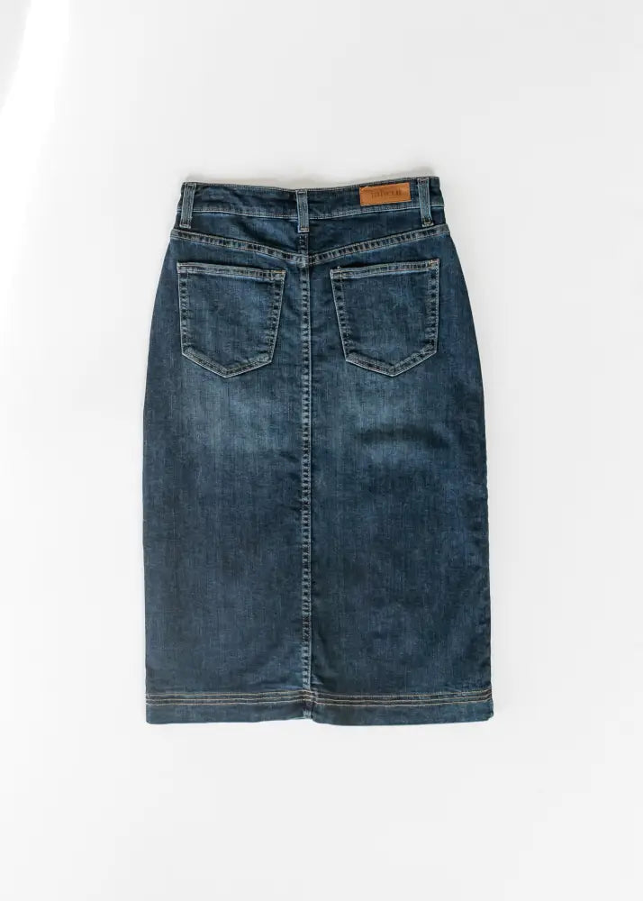 Back view of bryn dark wash straight denim midi skirt in dark blue with two pockets and brown leather brand tag