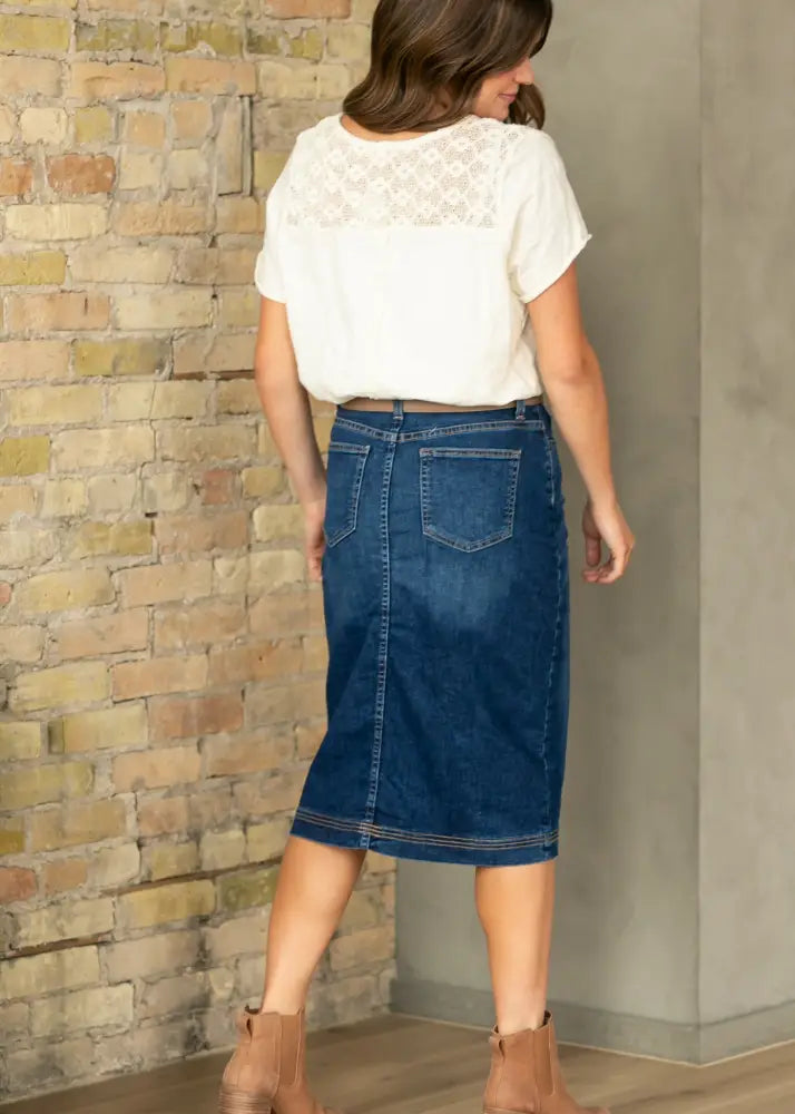 Back view of bryn dark wash straight denim midi skirt featuring blue denim fabric, back pockets, and a straight hemline