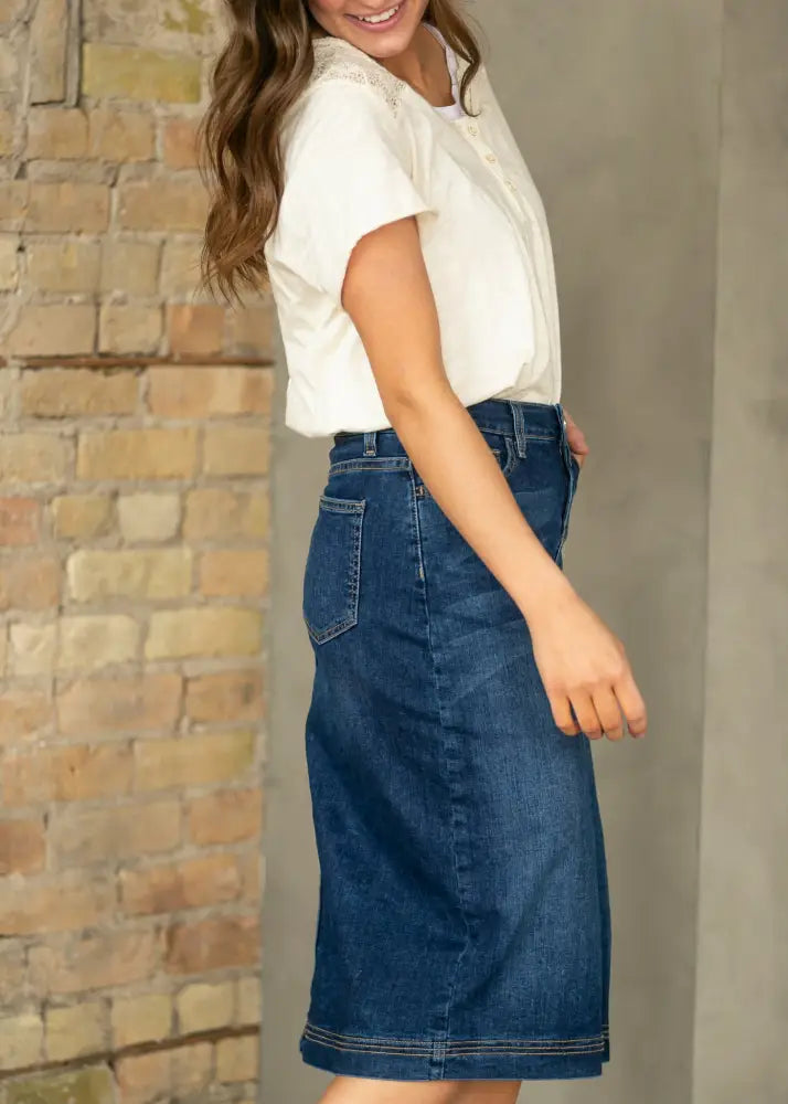 Bryn dark wash straight denim midi skirt in classic dark blue with visible stitching and button fly mid-thigh length