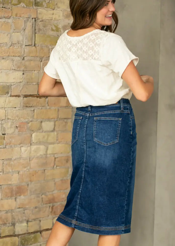 Back view of bryn dark wash straight denim midi skirt with two pockets and subtle stitching on mid-thigh length hem