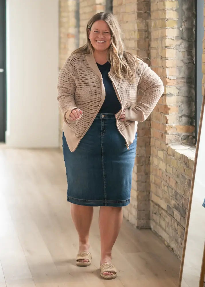 Beige knitted cardigan with textured open front worn over navy top paired with bryn dark wash straight denim midi skirt