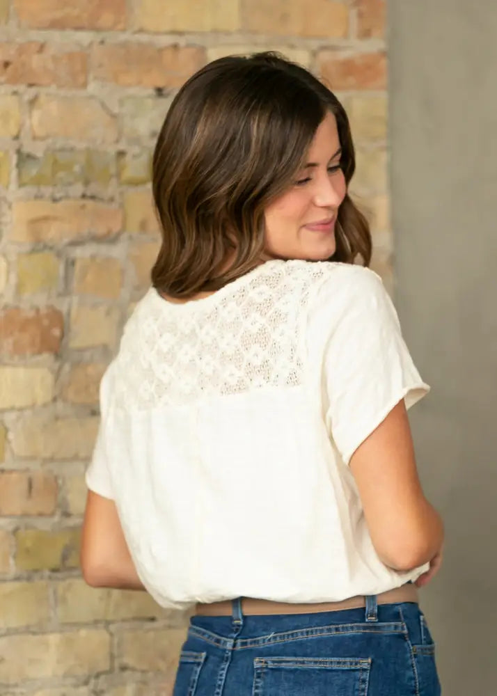 White short-sleeved blouse with delicate lace detailing on the back paired with bryn dark wash straight denim midi skirt