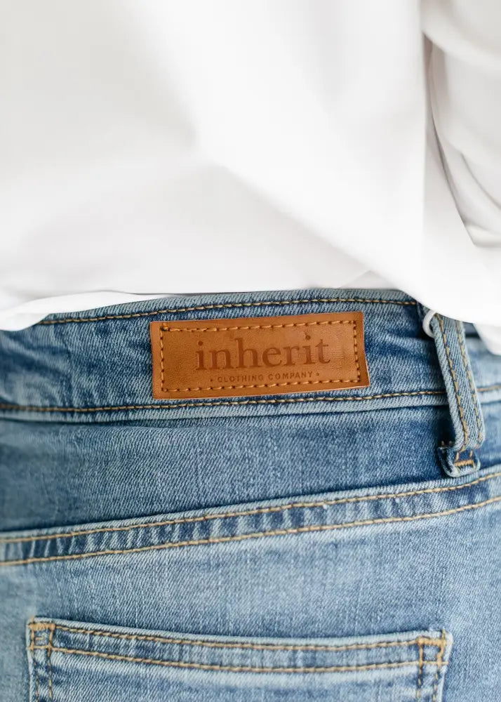 A tan leather patch stitched with inheri on medium-wash blue denim of bryn light wash sustainable denim midi skirt back