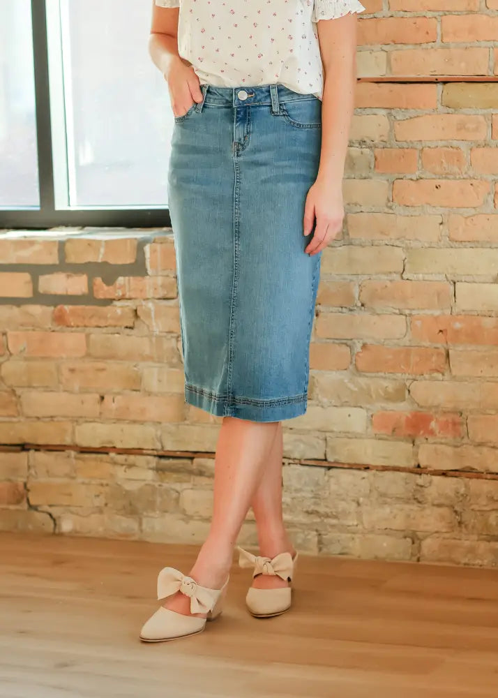 A mid-thigh length bryn light wash sustainable denim midi skirt in classic light blue with visible stitching and belt loops