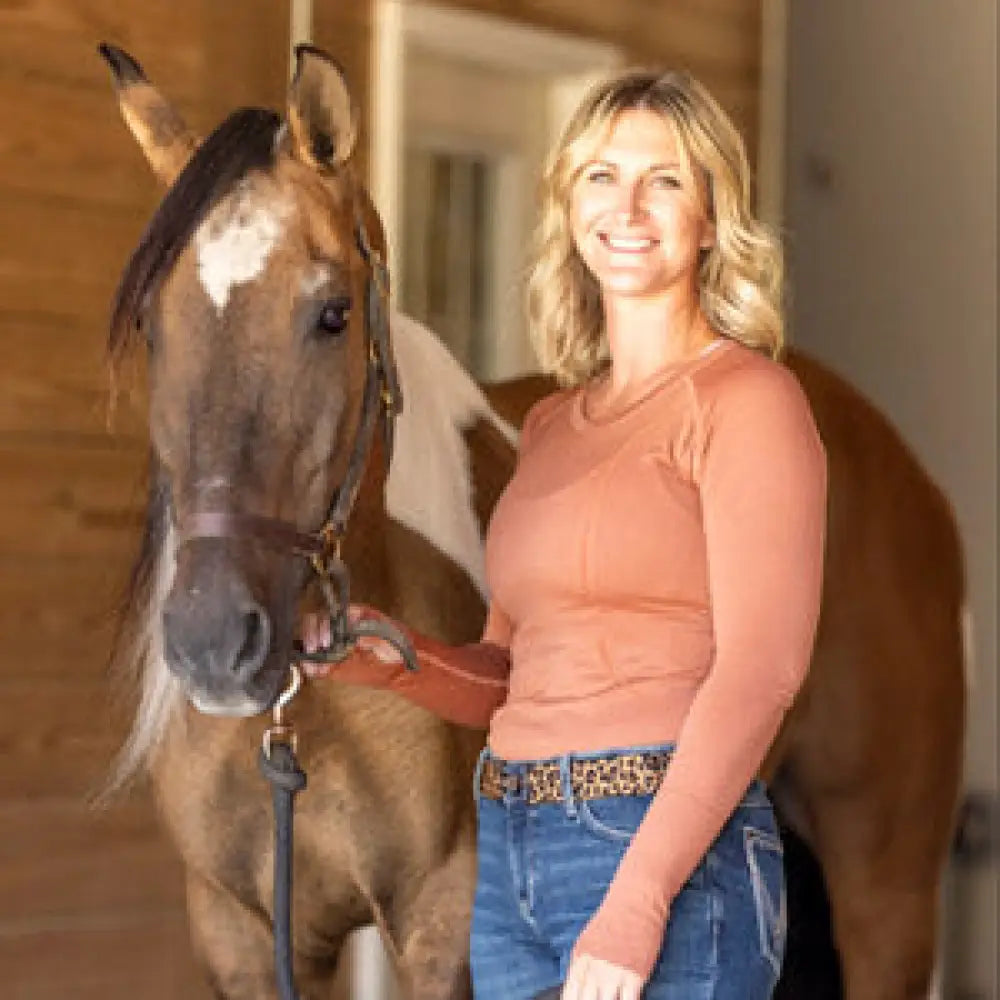 A woman wearing a rust-colored btr active seamless upf 30 sun protection baselayer and blue jeans