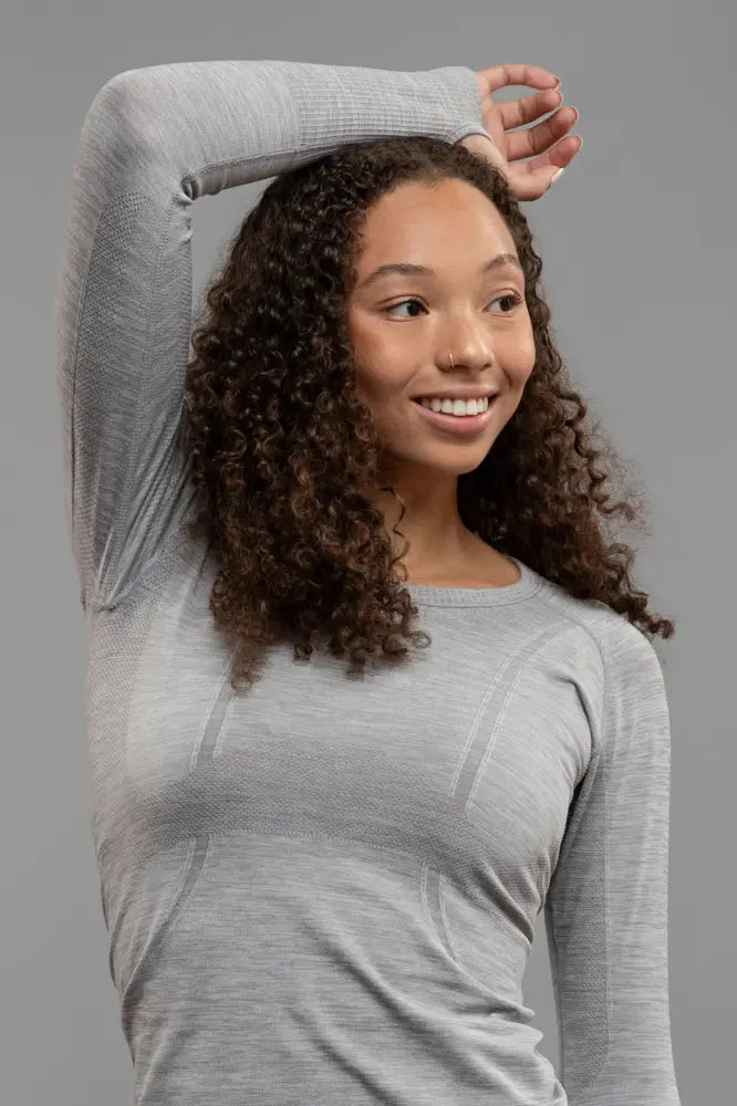 A woman wearing a light gray btr active women’s seamless upf 30 sun protection baselayer top with texture and seam detailing