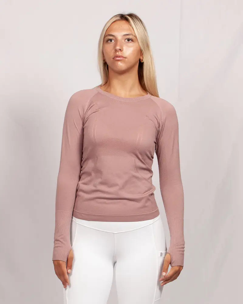 A soft rose-colored long-sleeved seamless upf 30 sun protection baselayer top with ribbed cuffs by Btr Active Women’s