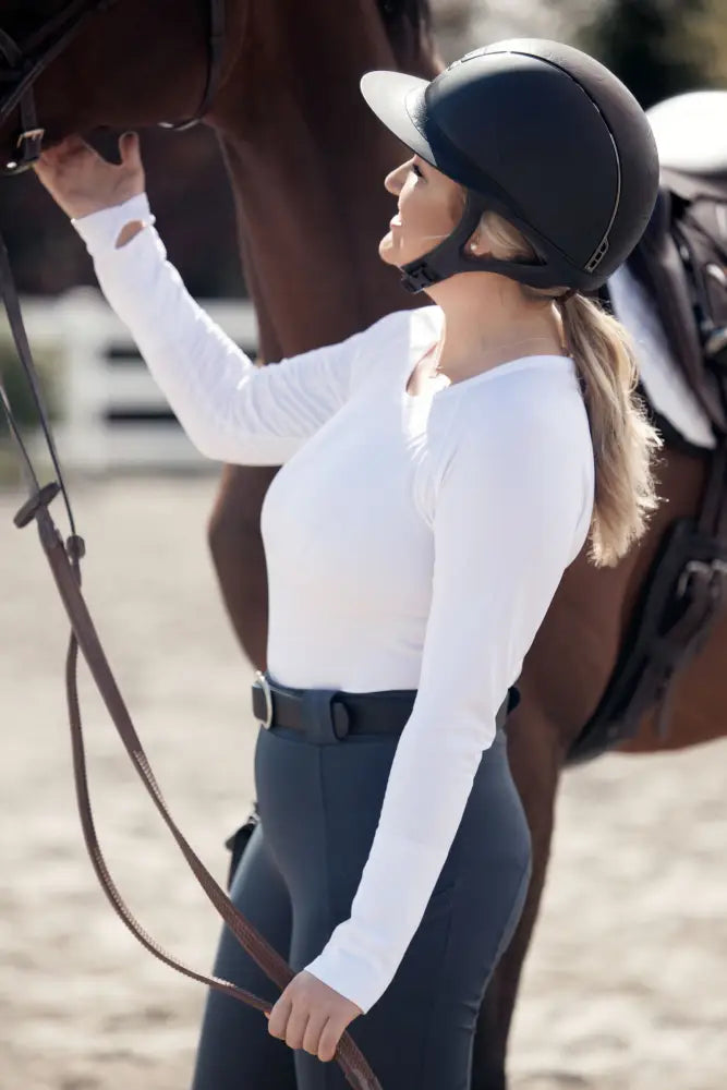 Black equestrian helmet with smooth glossy finish and adjustable straps paired with btr active women’s seamless upf 30 baselayer