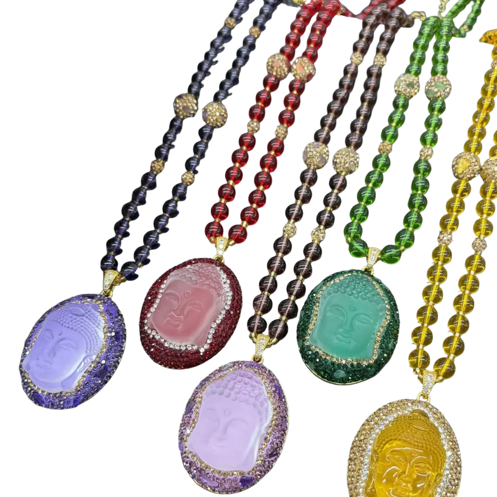 A collection of buddha pendant necklaces with colored resin faces, rhinestone accents, gold-toned metal, and beaded chains suitable for all applicable age groups including use with a sesame clip