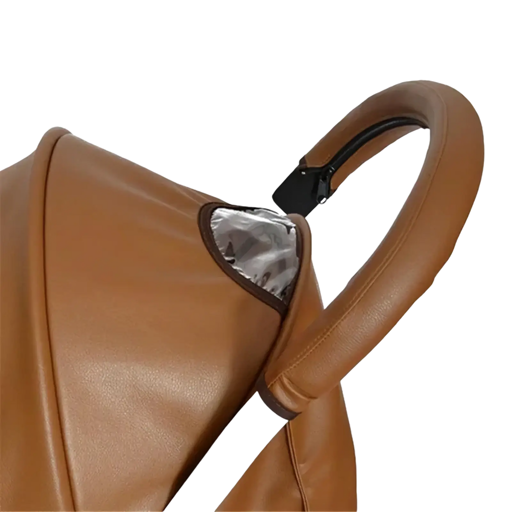 Brown leather bugaboo bee stroller handle cover with black clip and silver reflective panel visible from the back side