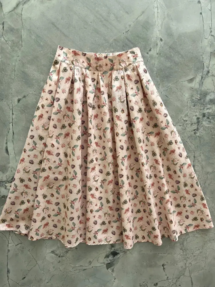 Bugs print cotton pleated doris skirt with pockets featuring a soft pink floral design and delicate leaf patterns
