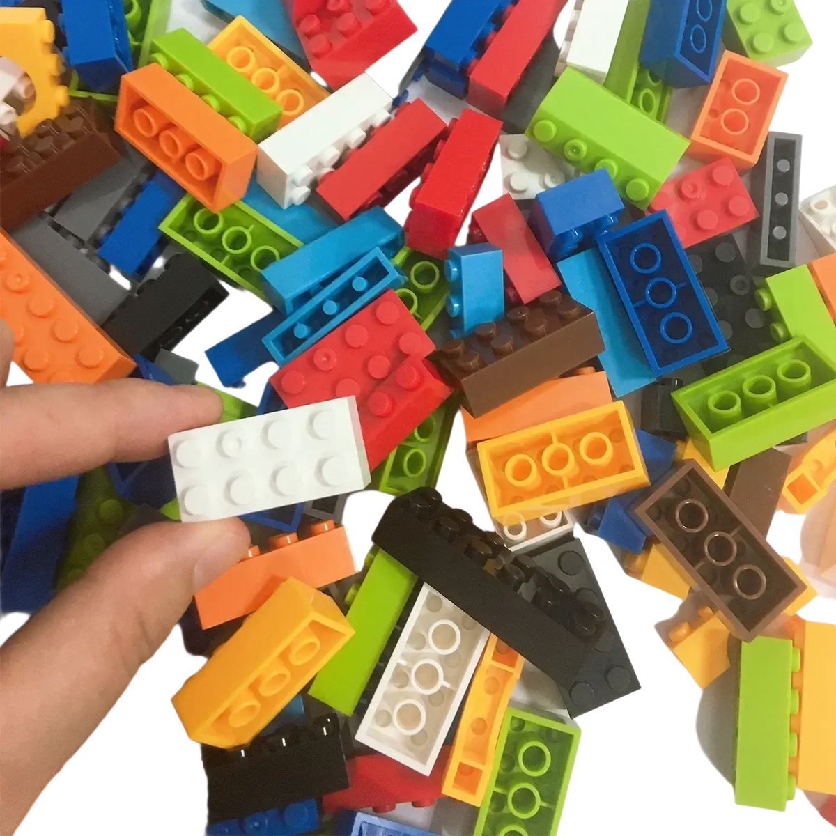 A hand holds a white rounded diy creative building block among colorful plastic diy creative building blocks