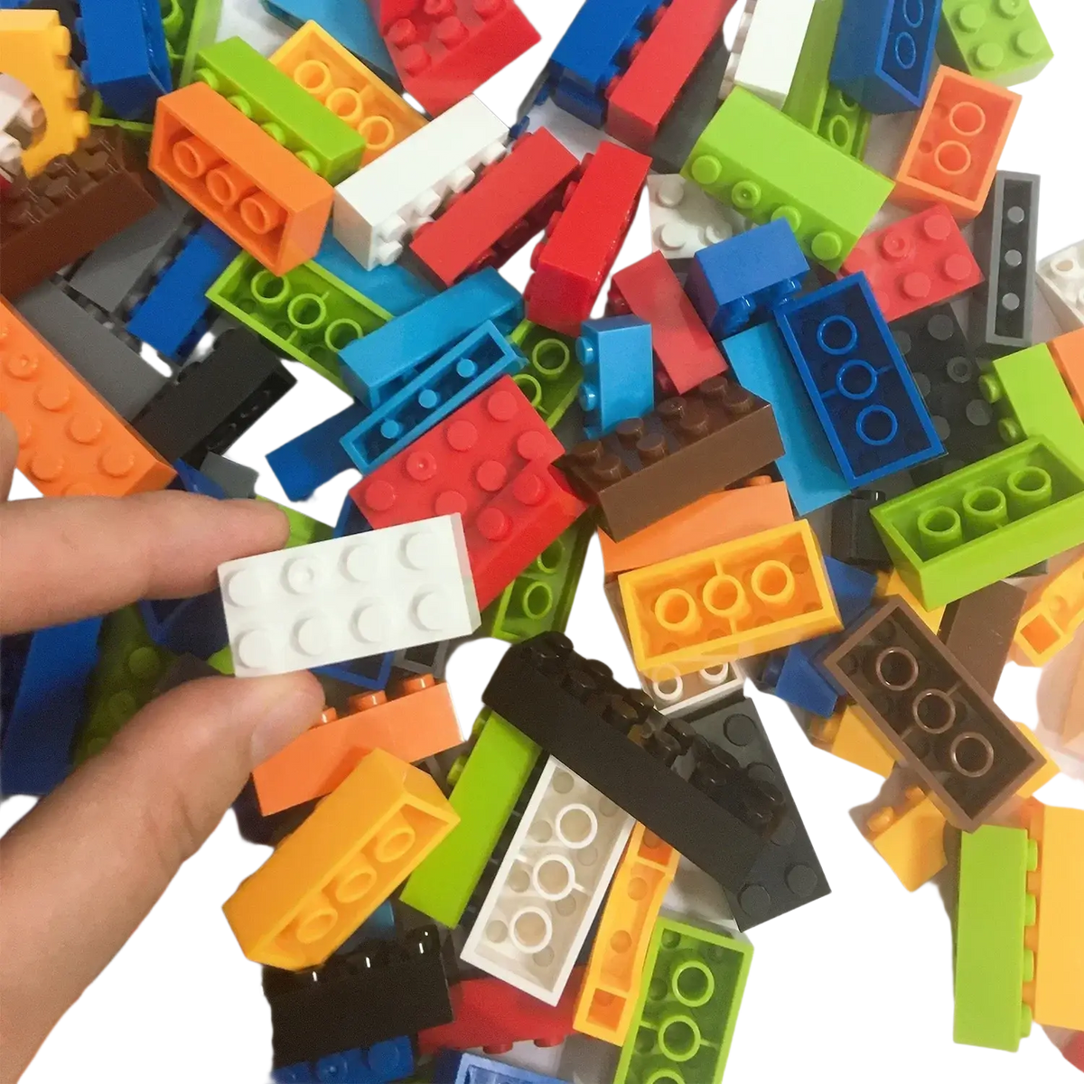 A hand holds a white plastic building block with six studs surrounded by colorful diy creative building blocks