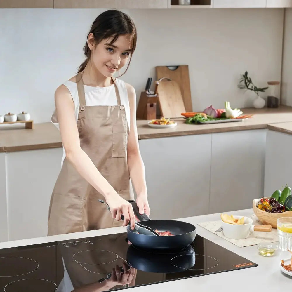 Black non-stick frying pan with sleek modern design and sturdy handle shown with 35 inch 5 burner electric ceramic cooktop