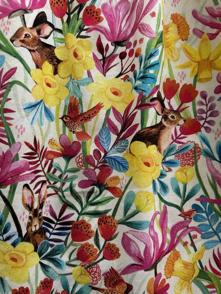 A vibrant bunnies and floral print cotton fit and flare dress with brown rabbits and colorful flowers on a light background