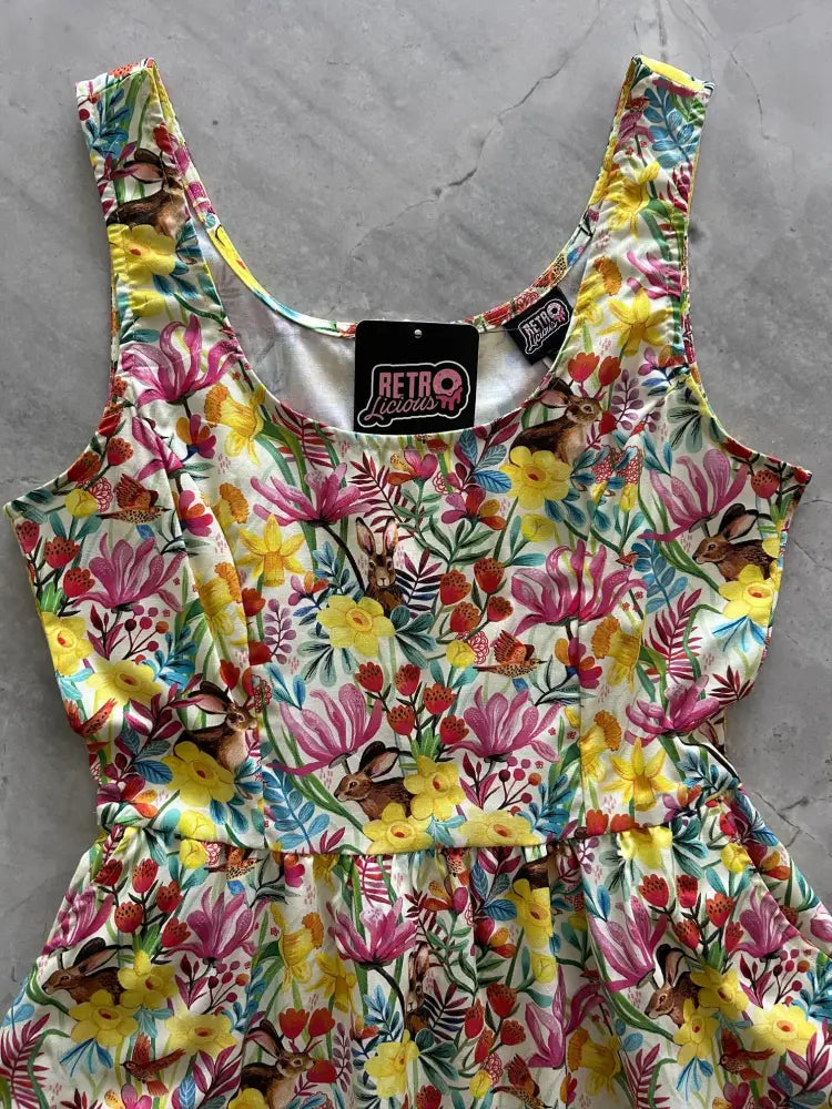 A vibrant sleeveless fit and flare cotton dress with bunnies and floral print in yellow pink red and green hues