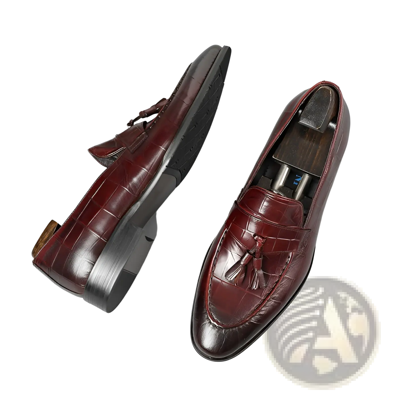 Burgundy crocodile embossed leather tassel loafers with a polished finish and black rubber soles