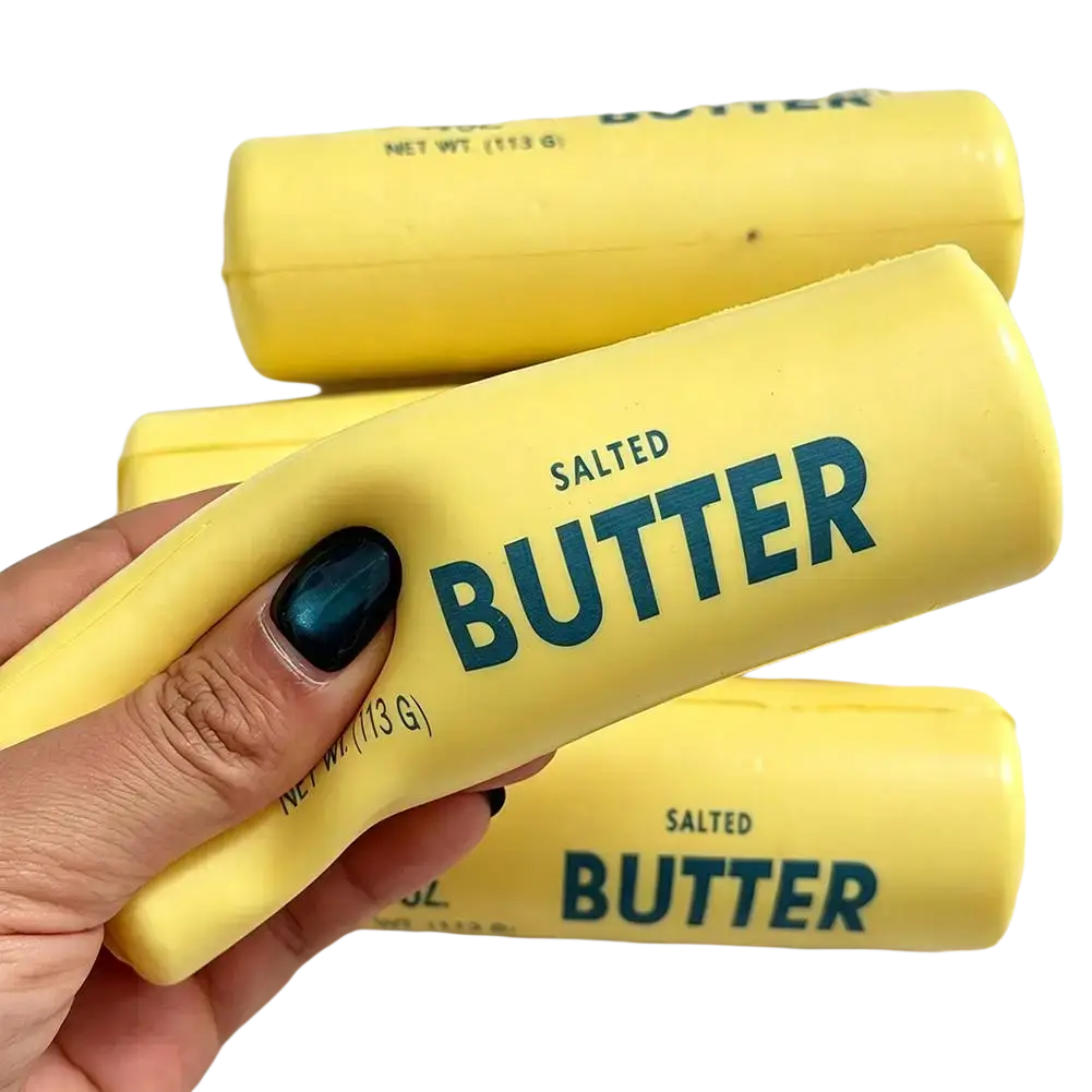 Yellow butter stick slow rising squeeze toy with teal lettering and matte finish held in hand