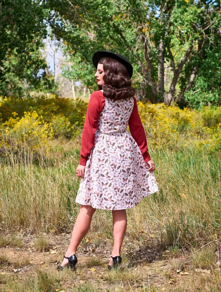 A woman wears a butterfly vintage cotton midi dress with a white base, red sleeves, and black heels