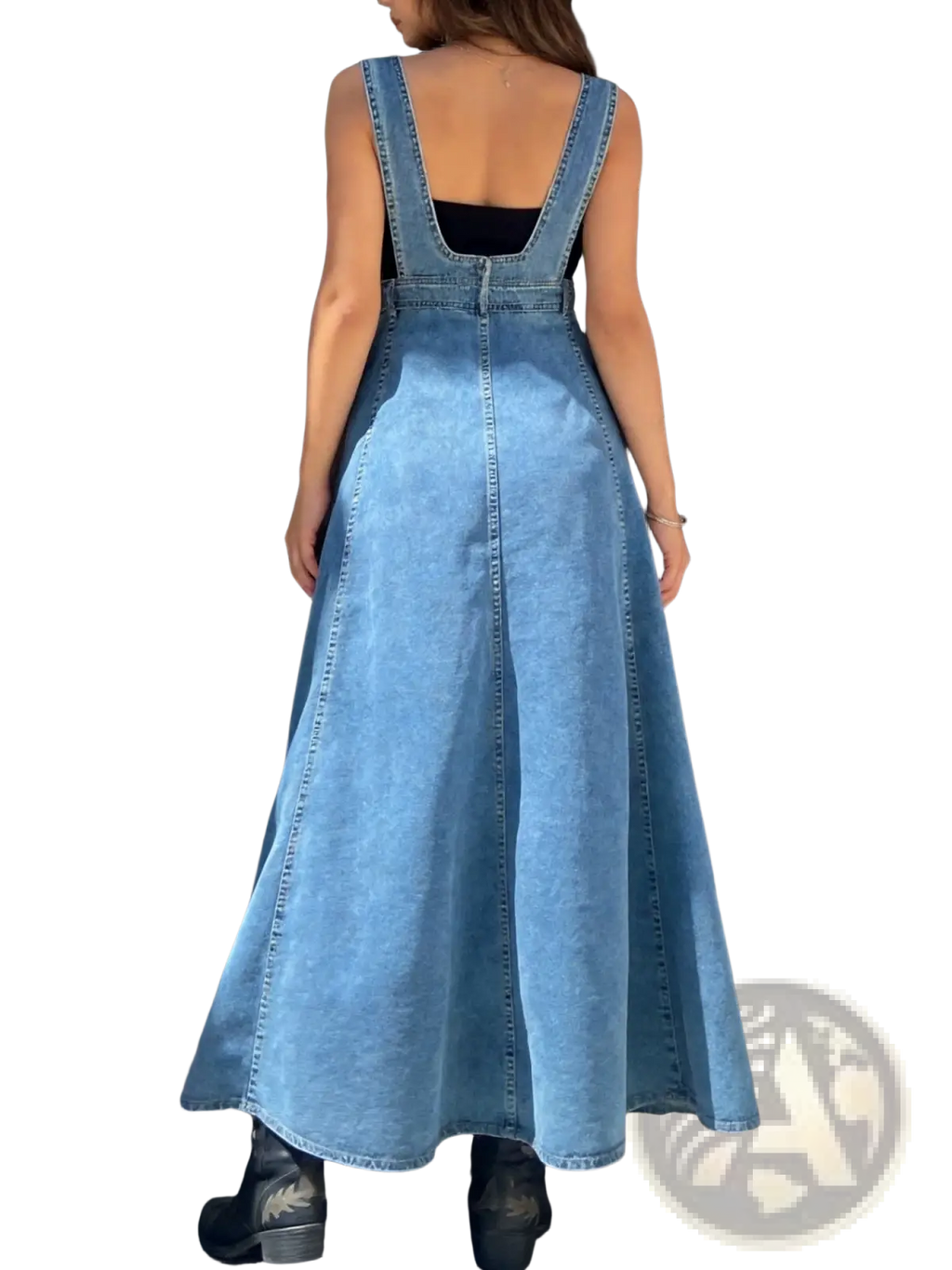 Light-wash denim overall dress with back zipper and wide straps worn over black top showcasing back view