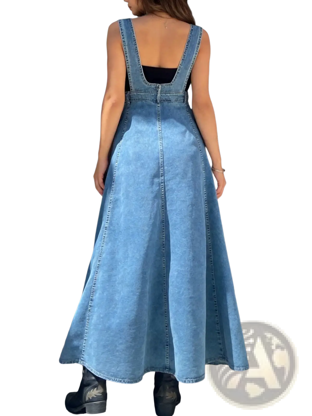 Light-wash denim overall dress with back zipper and wide straps worn over black top showcasing back view