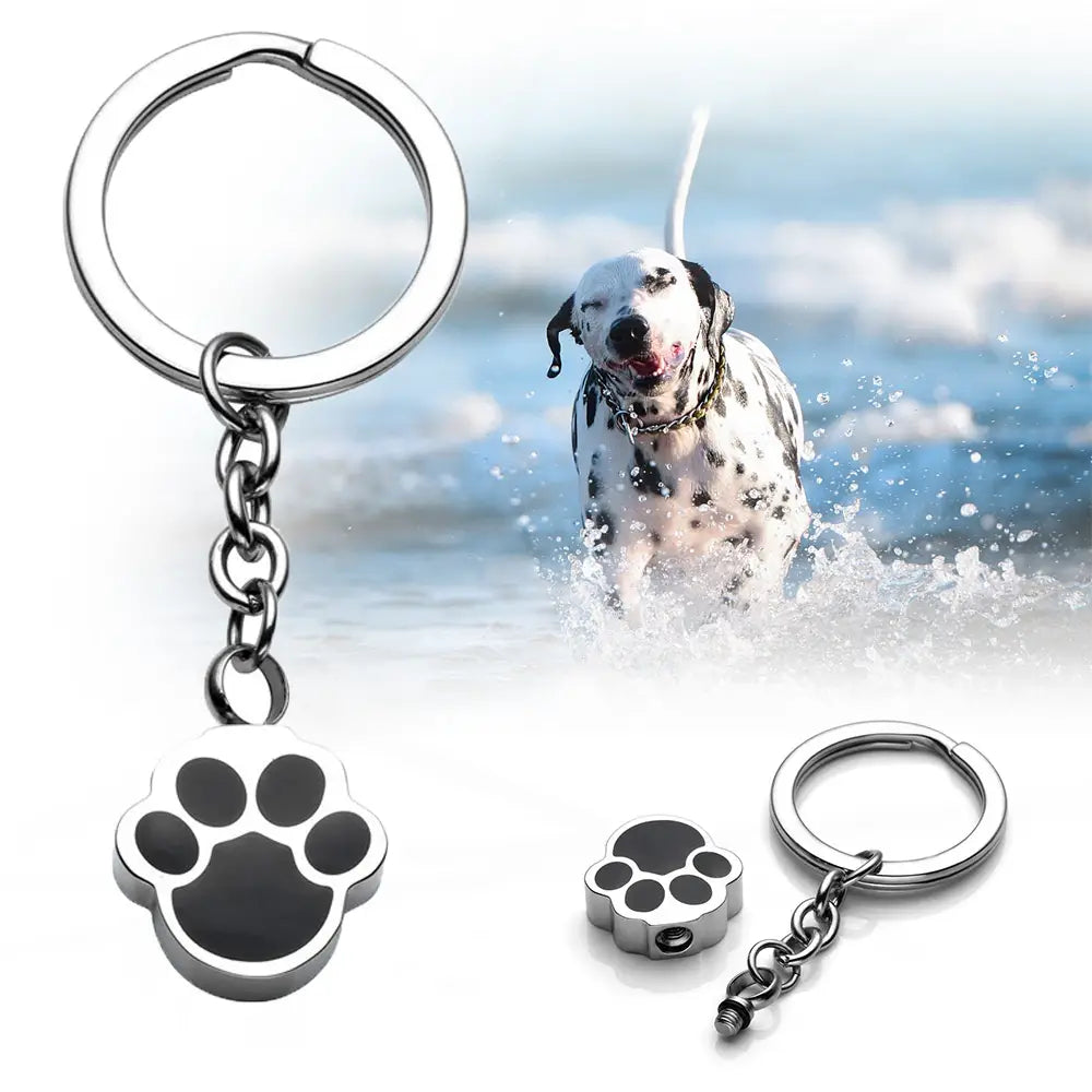 Silver dog paw urn keychain cremation memorial pendant with black enamel fill and silver paw print design.