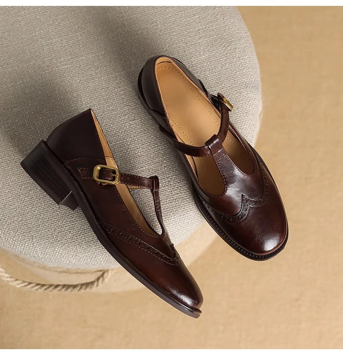 Braune Leder-Brogue-Mary-Jane-Pumps mit klobigem Absatz mit T-Riemen und goldfarbenem Schnallenverschluss.