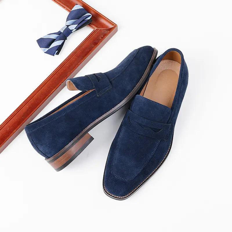Men’s navy blue suede penny loafers with classic design and brown leather soles for casual wear.