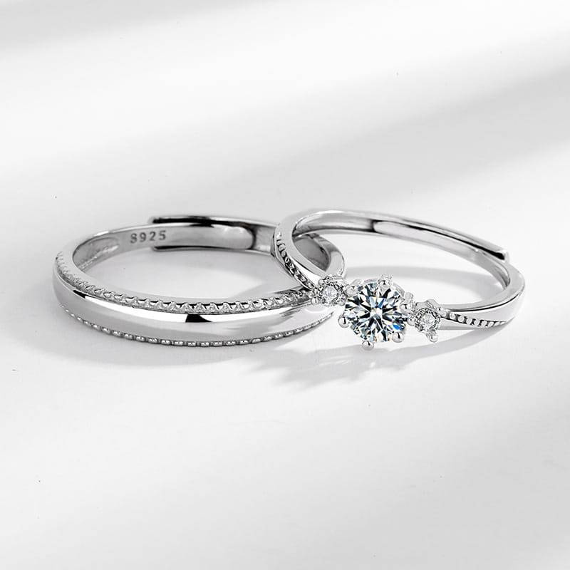 A sleek silver 925 sterling silver love at first sight diamond couple ring set featuring a delicate band with micro-paved stones and an elegant three-stone design centered around a prominent round-cut diamond.