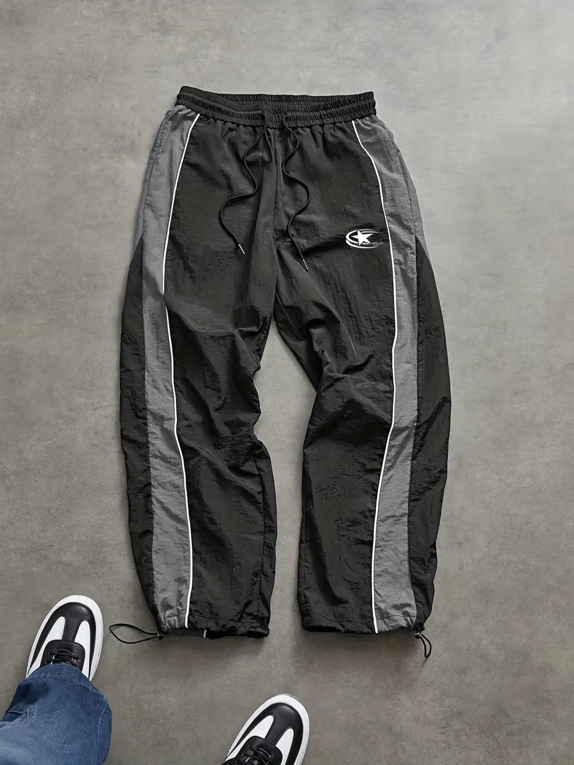 Men quick dry athletic track pants in black and gray with white piping along the side panels featuring a drawstring waistband and adjustable ankle cuffs.