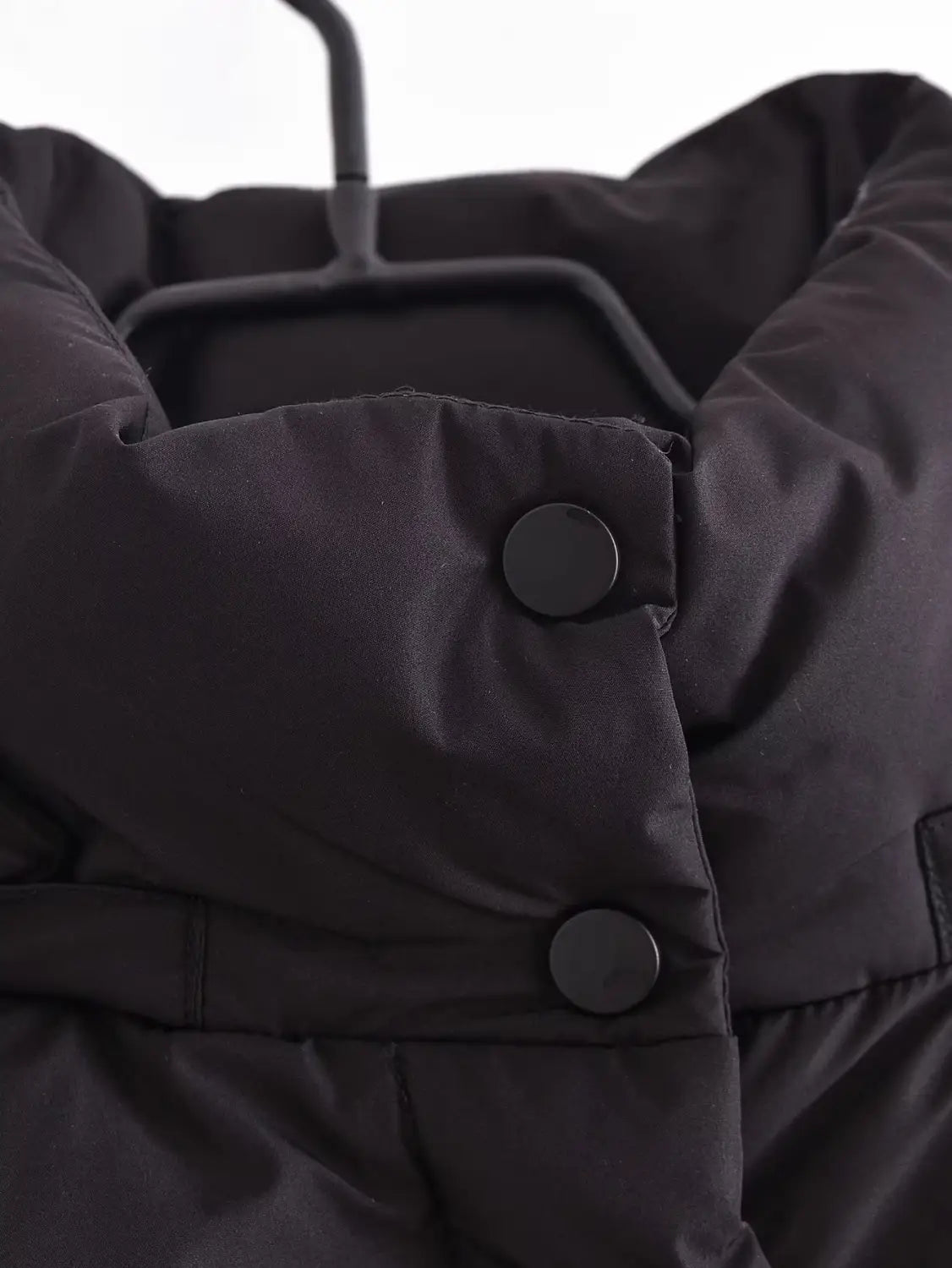 Black quilted hooded puffer coat featuring a black puffer jacket design with quilted fabric and matching black buttons.