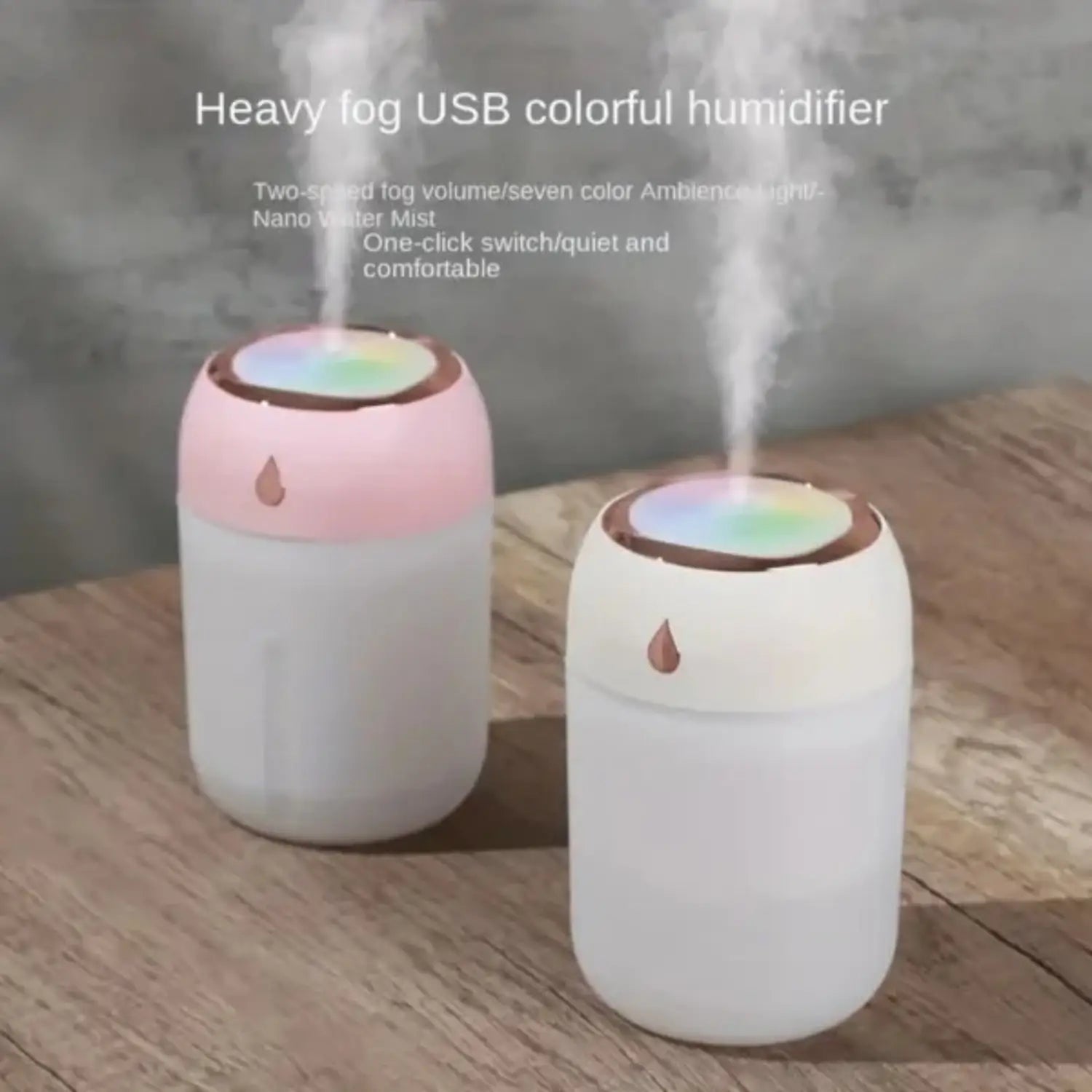Ultrasonic USB desktop humidifier in pink and white with a rainbow-colored top emitting heavy fog and featuring a night light.