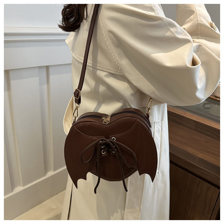 Brown bat wing heart crossbody bag featuring lace-up detail and adjustable strap for versatile wear.