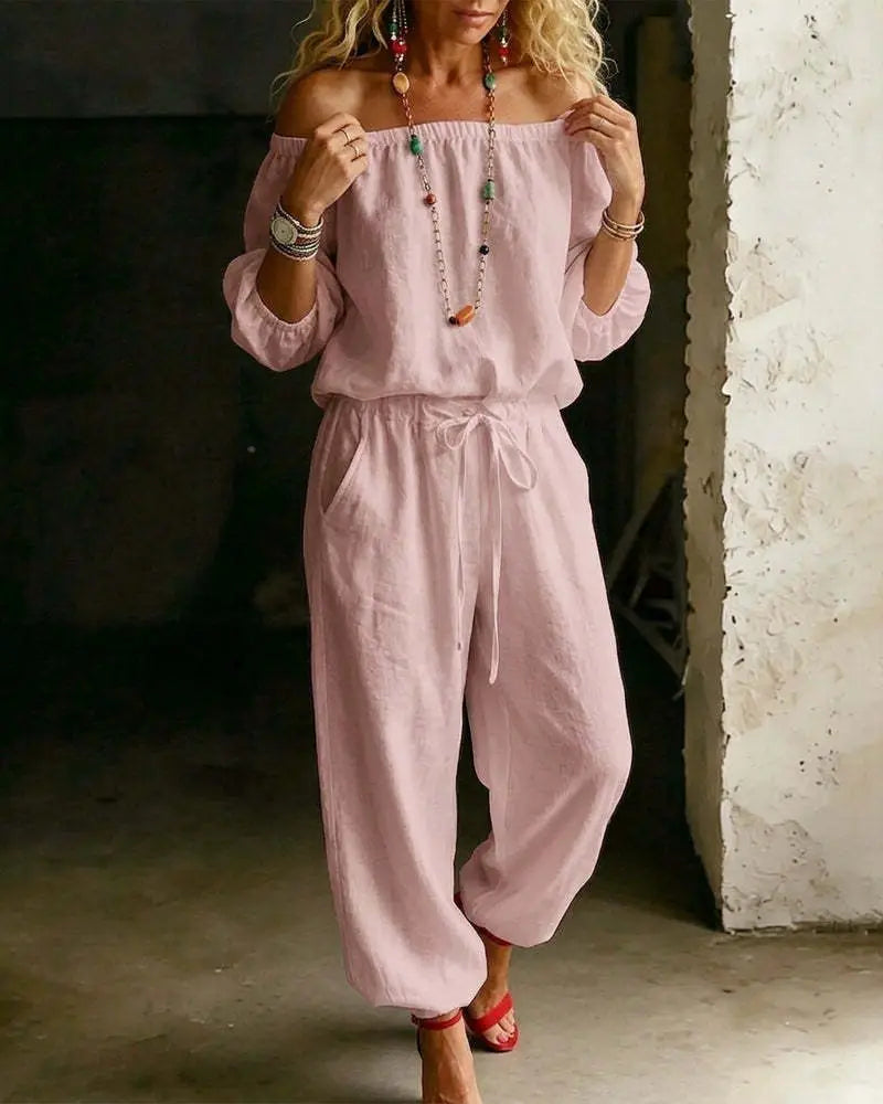 A soft pink linen off-shoulder jumpsuit set with a drawstring waist and relaxed tapered legs.