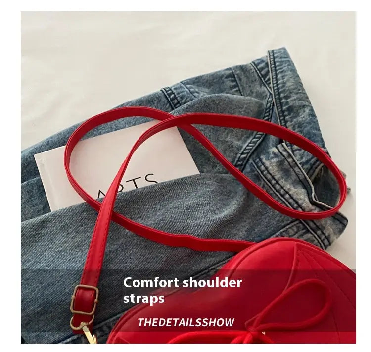 red comfort shoulder straps with a gold toned buckle on the bat wing heart crossbody bag with lace up detail