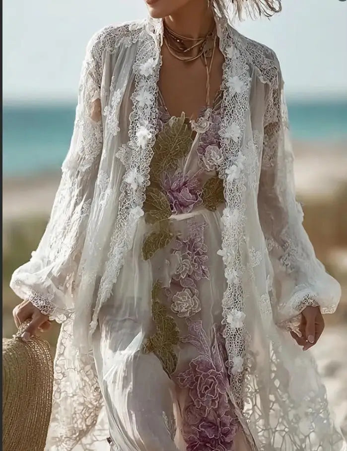Ein Vintage-Blumenmuster-Midikleid mit langen Ärmeln, das ein fließendes weißes Spitzenkleid mit zarter Blumenstickerei in sanften Violett- und Grüntönen sowie kunstvollen Häkelverzierungen entlang der Kanten zeigt.