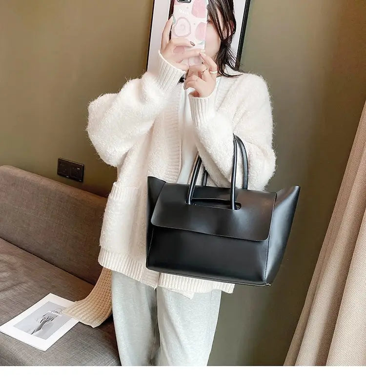 Black leather vintage structured tote bag with a rectangular shape and short top handles designed for everyday use.