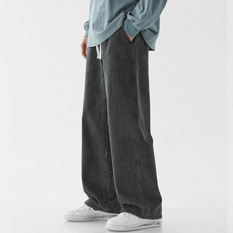 Men’s relaxed fit drawstring wide leg denim jeans in dark gray with a tapered fit and white drawstrings at the waist.