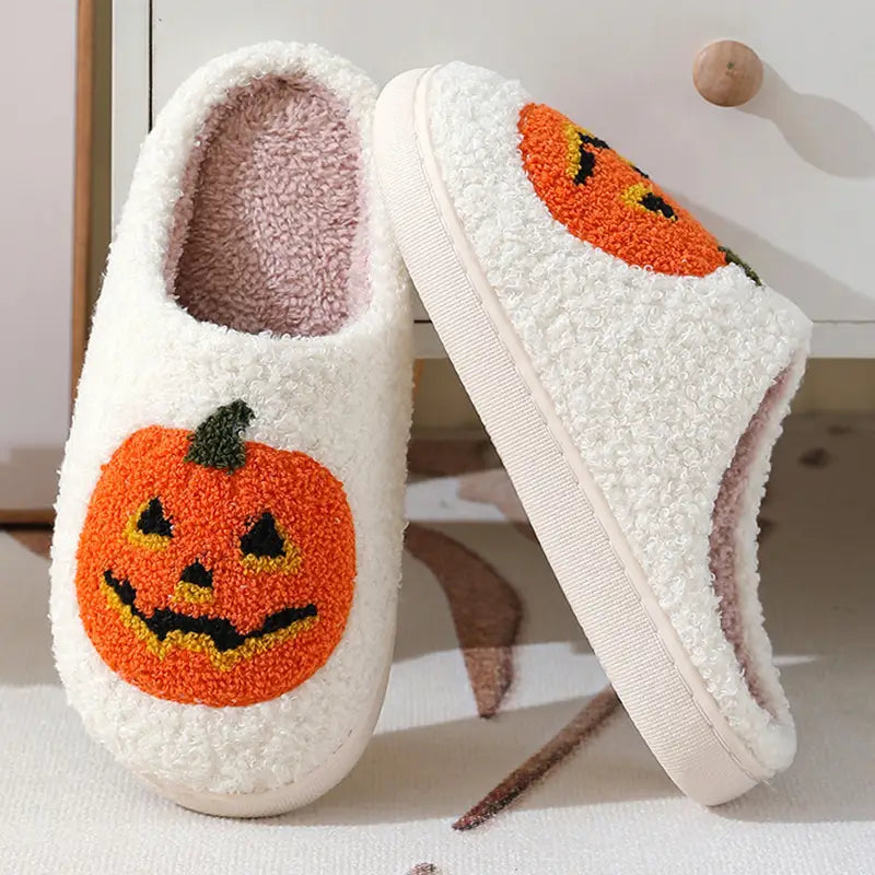 White plush jack-o-lantern embroidered halloween slippers featuring orange pumpkin faces on the front.