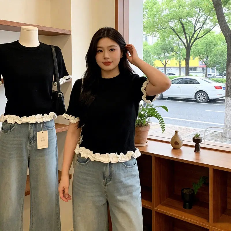 Black short-sleeved knit top with white ruffled trim at the hem and cuffs featuring a colorblock design.