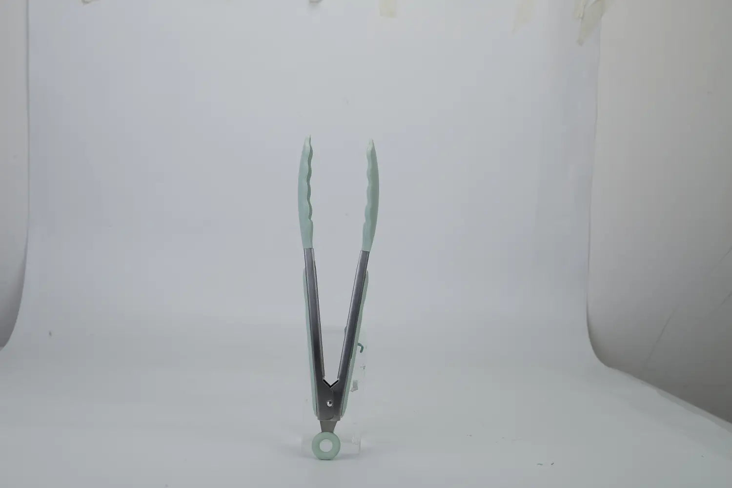 Light blue silicone-coated metal tongs with a rounded base from an 11-piece silicone cooking utensil set with wood handles.