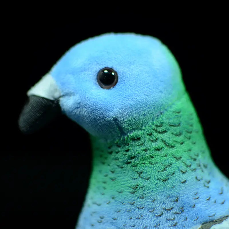 Une peluche de colombe bleue et verte de 19 cm, avec une surface texturée douce et des yeux en perles noires.