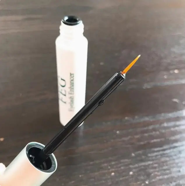 black eyeliner pencil with a fine pointed tip and an orange-tipped applicator from feg eyebrow enhancer growth serum for longer brows.