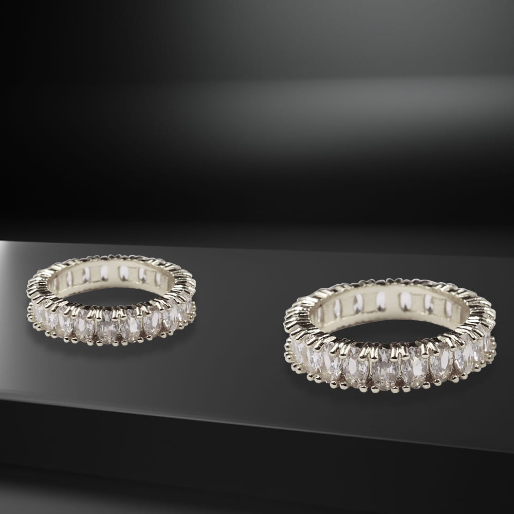 Two silver-toned eternity rings from the elegant eternity gemstone and pearl jewelry collection featuring a continuous band of oval-cut clear stones set in an intricate prong design.