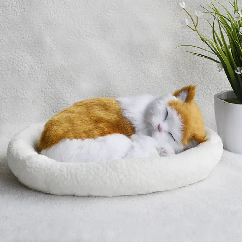 A plush orange and white realistic breathing cat figurine nestled comfortably in a soft round white pet bed.