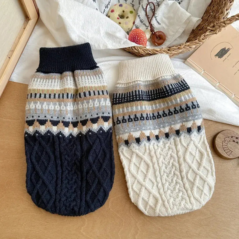 Zwei gestrickte Hundepullover aus marineblauem Zopfmuster und cremefarbenen Farbtönen mit aufwendigen geometrischen Mustern; weicher Strick im Stil Fair-Isle-Blau für Heimtierbedarf.